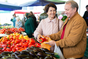 Elderly man and woman buy pepper at an open market