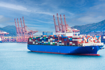 Aerial view on the large blue cargo container ship, fully loaded with colorful boxes, on her...