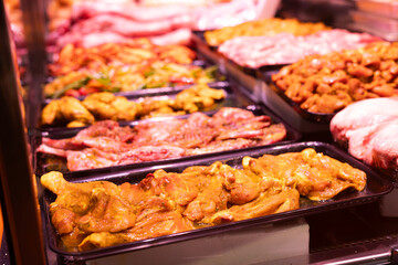 Meat department of store sells chicken hips marinated with addition of curry seasoning.