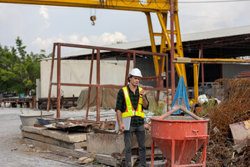 Male civil engineer stands next to a concrete mixer or bucket checking the quality of cement to...
