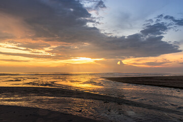 Kuta Beach during beautiful orange sunset with dramatic clouds on sky on Bali. Stunning seascape