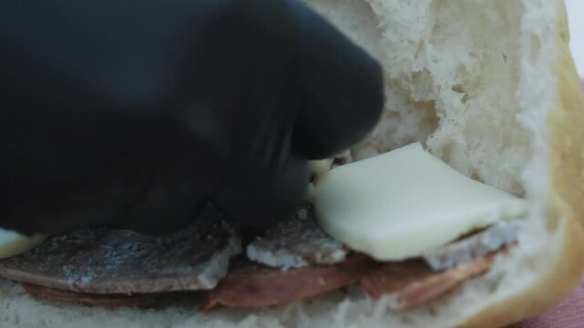 In the close-up, the inside of the toast bread is being prepared. The bread is filled with sausage, roasted meat, and finally kashar cheese. It shows the stages of making a rich toast.