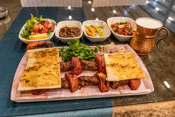 Meal in Turkey - dish of Adana kebab with side dishes and ayran drink