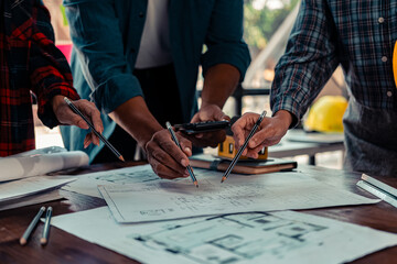 A team of industrial engineers meets to analyze machine blueprints. Discuss the project on the table, use the laptop to draw the building design project in the office. construction concept
