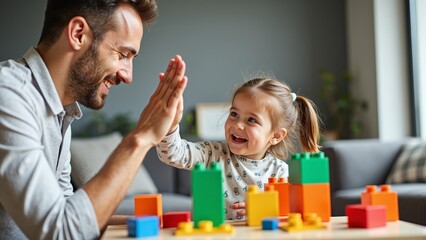 A joyful father and daughter share a high-five while playing with colorful building blocks at home.