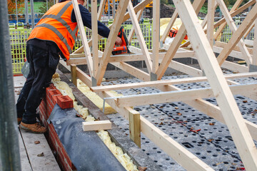 Construction worker assembling wooden frame on building site with safety gear and tools in use