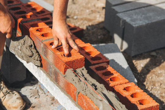 Close-up of builder hands laying bricks on building site, showing masonry techniques emphasizing craftsmanship and construction skills