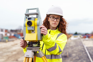 Portrait of female Surveying professional using advanced equipment to measure land on  construction site