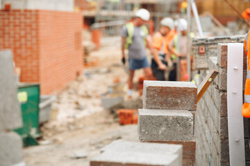 Construction workers build sturdy wall using concrete blocks