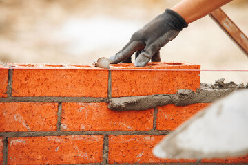Close-up of hands of Skilled bricklayer laying bricks with precision 