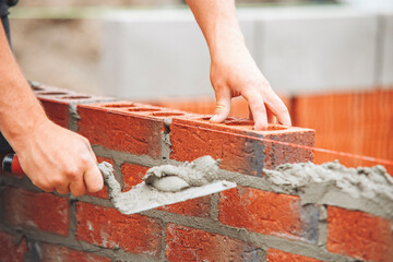 Skilled craftsman laying bricks with mortar to construct sturdy wall 