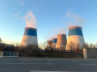 The heating plant pipes along the roadway release abundant steam from both thin and thick pipes on a sunny day with a blue sky