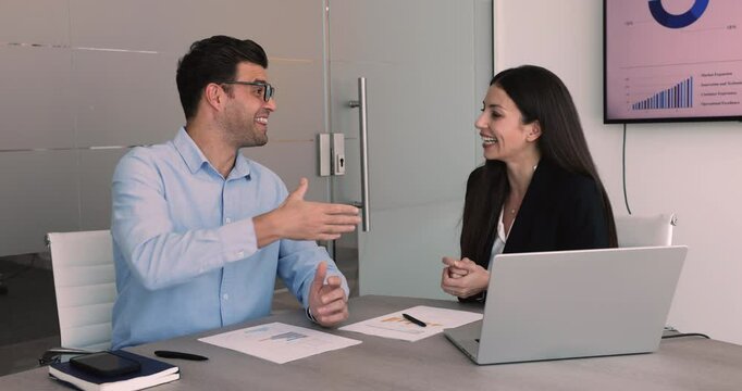 European and Arabian business partners sit at desk with papers and laptop, lead talk, make business deal, shaking hands as symbol of agreement, trust, successful collaboration, partnership conclusion