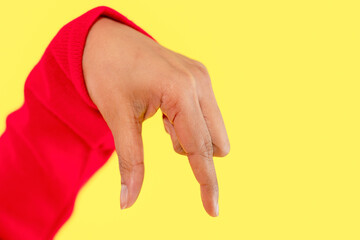Hand gesture showcasing creative expression against a vibrant yellow background during a sunny day