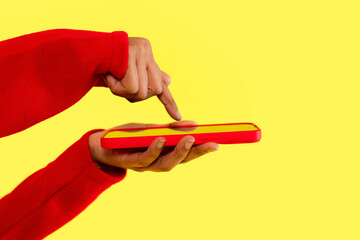 Person interacting with smartphone while wearing  red sweater against a bright yellow background...