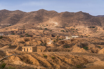Panoramic view of Matmata, Tunisia, featuring iconic troglodyte homes and living caves, surrounded by arid desert landscapes and rocky terrain.
