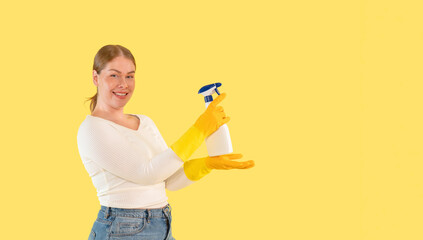Bright and cheerful woman holding cleaning spray bottle while wearing yellow gloves in a vibrant setting
