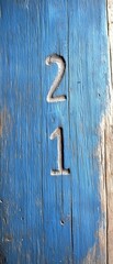 A weathered blue surface features carved numbers 2 and 1, showcasing a rustic texture and color contrast.