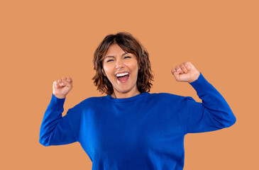 Joyful celebration expressed by a woman wearing a blue sweater, celebrating success with raised...