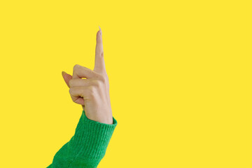 Hand signaling upwards with a raised index finger against a vibrant yellow background in an...