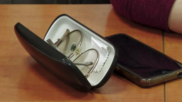 There is an open glasses case on the table. Close-up.