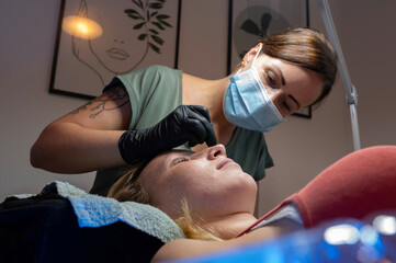 Beauty Close-up of a young woman having her eyelashes microblading brow lash lifting enhanced with an eyelash lift by a beautician in a beauty salon. Shaping eye lash correction