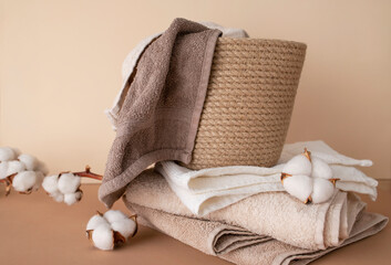 Natural wicker basket with cotton towels, branch and cotton flowers on beige background....