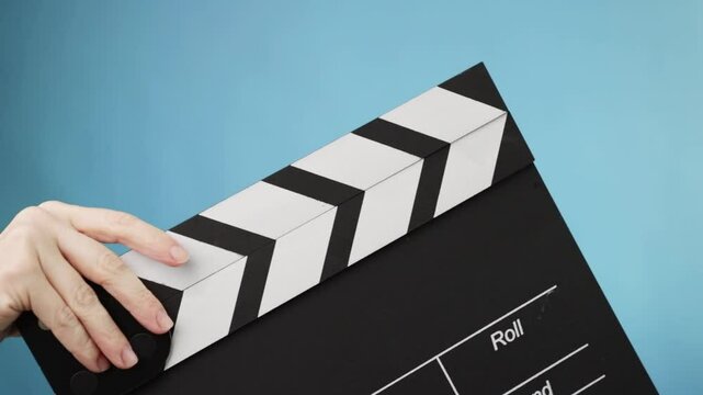 Closeup of a director's hand using a clapperboard, starting a new film scene in a studio