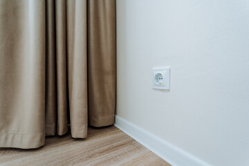 The interior of a bedroom featuring a decorative curtain and an electrical socket conveniently located on the wall, enhancing both functionality and style in the overall design