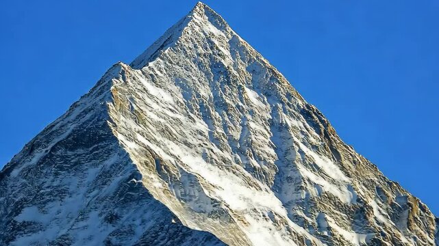 Snow-covered peak rises dramatically against a clear blue sky showcasing the beauty of nature's grandeur