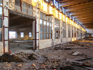 An abandoned industrial space with exposed brick walls, debris on the floor, wooden beams, and...