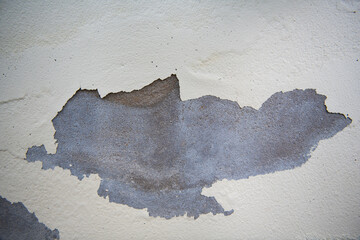 Peeling paint wall reveals textured surface with gray and white colors, creating artistic effect