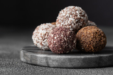 Assortment of gourmet handcrafted vegan chocolate truffle candies on dark marble background from premium confectionary. Handmade bonbons chocolatier concept. Horizontal banner with copy space