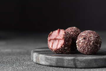 Artisan chocolate truffle candies with berry and fruit filling on dark marble background from confectionary. Handmade or handcrafted bonbons, chocolatier concept. Horizontal banner, copy space