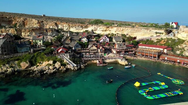 Drone aerial view at Popeye Village in Malta, the Mediterranean Sea, and the village houses near the beach.