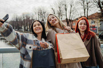 Group of three teenage girls friends take self portrait with shopping bags	