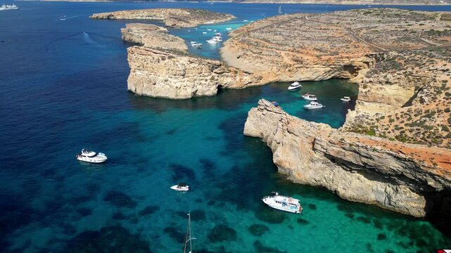 Aerial drone view of the Blue Lagoon on Comino Island, Malta. Panorama of the Mediterranean Sea, yachts, boats, and stunning cliffs.