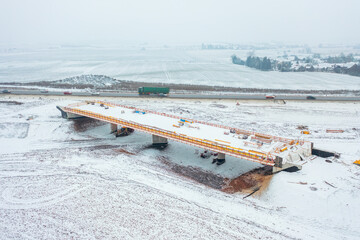 Construction of a bridge over the newly developed Highway D35, captured from above with a snowy construction site.