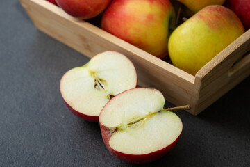 Fresh small organic red apples in a wooden crate on grey table background