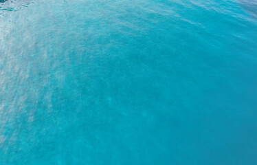 Drone view of the transparent turquoise waters of the Adriatic Sea shimmering under the sun. The seabed with visible stones adds depth and natural beauty, perfect for travel and nature themes.