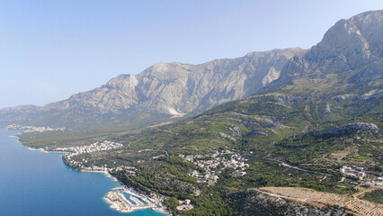 Fototapeta premium A picturesque coastal village nestled between majestic mountains and the deep blue sea. A serene and idyllic landscape perfect for travel, adventure, and nature exploration. Croatia