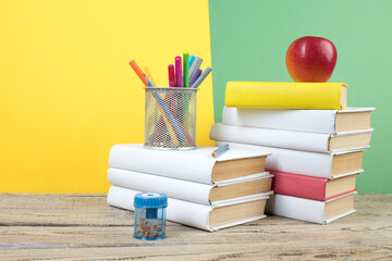 Books stacking. Books on wooden table and green, yellow background. Back to school. Copy space for ad text.