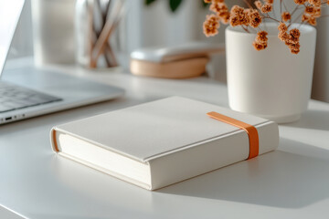 Elegant beige journal with orange band on minimalist white desk