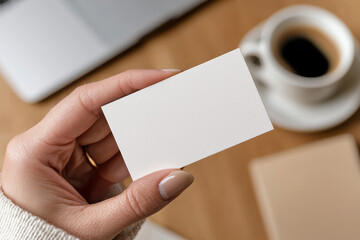 Close-up of blank business card held by female hand over coffee