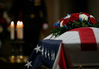Draped American flag on military funeral casket with candlelit background