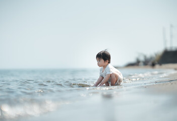 桜島をバックに浜辺で砂遊びをする一歳の男の子