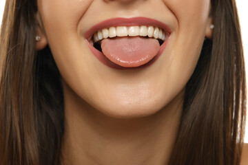 Obraz premium Close-up of young woman showing her teeth and sticking out tongue, wearing pink lipstick, partial face view focused on mouth area.