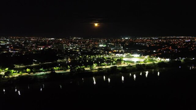 Cidade em noite de lua cheia beira rio