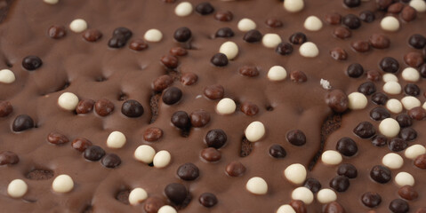 Chocolate brownie cake texture background sprinkled with white and dark balls, brounie banner