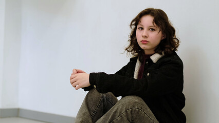 A thoughtful girl sits with her hand on her forehead in a quiet environment. This image explores...